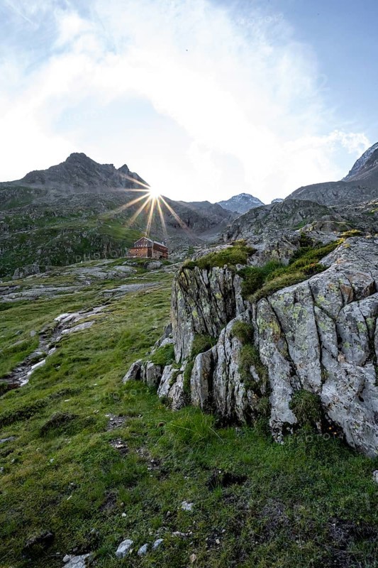 Mountain hut Elberfelderhütte in front of a rocky mountain landscape, sun star in the morning, in the upper Gössnitz valley, Wiener Höhenweg, Schober group, Hohe Tauern National Park, Carinthia, Austria