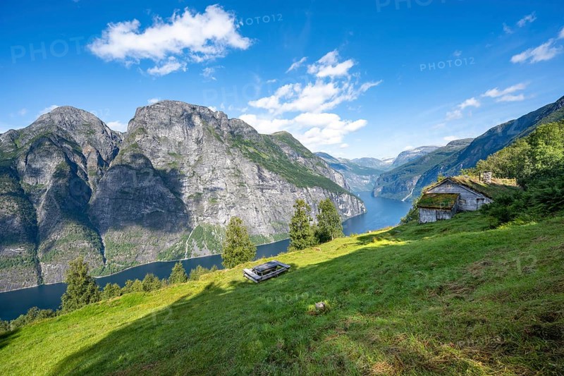 Blomberg Gård, historic mountain farm with grass roof on a steep mountainside above the Geirangerfjord, view of idyllic fjord landscape, near Geiranger, Møre og Romsdal, Norway