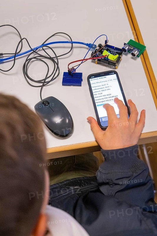 Child operating smartphone next to electronic devices on a table, Youth Research Centre Nagold, Germany