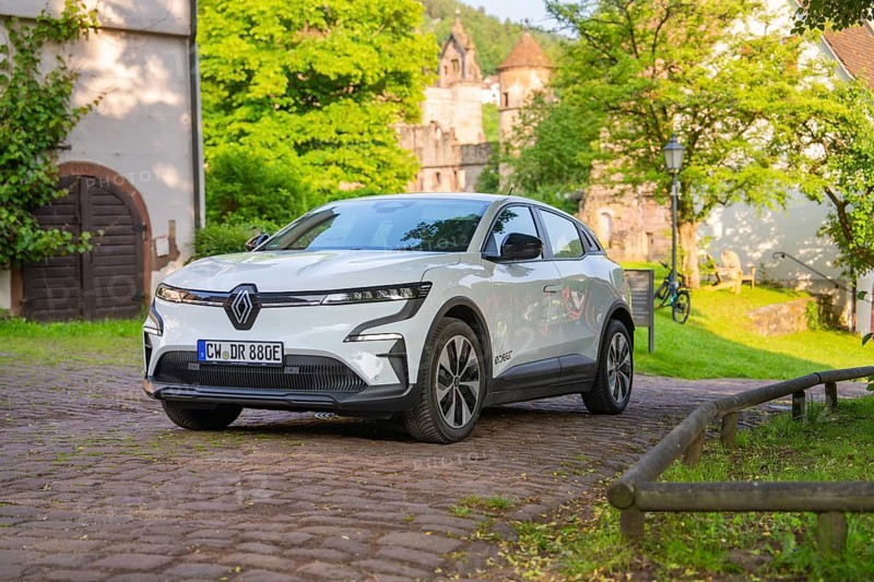 White car parked on a cobbled path in front of old buildings and a green summer backdrop, Renault Megane, Deer E Carsharing, electric car, Calw, Black Forest, Germany