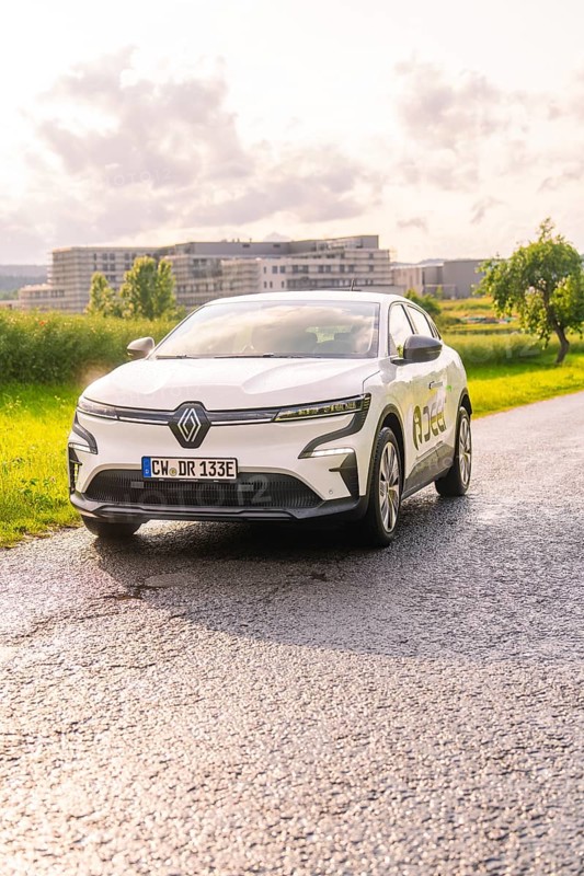 White Renault car on a road with fields and urban landscape in the background, Renault Megane, Deer E Carsharing, electric car, Calw, Black Forest, Germany