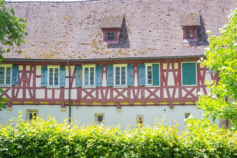 Historic half-timbered house with small windows behind green hedges, event and wedding location Lorch Monastery, Lorch, Germany