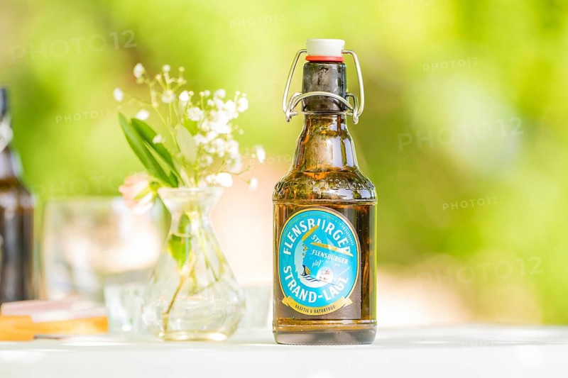 Bottle of Flensburger Strand beer on a table next to a vase of flowers in a green, natural setting, event and wedding location Kloster Lorch, Lorch, Germany