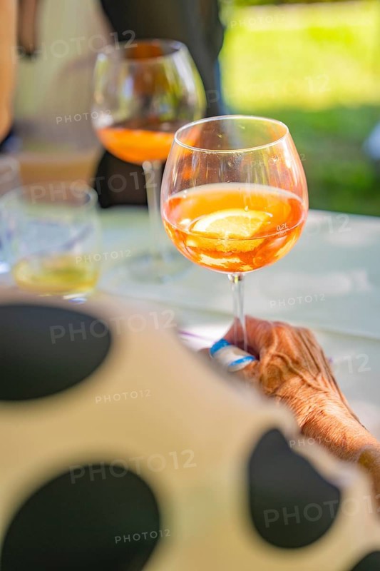 Person holding glass with orange coloured drink at a garden party in summer atmosphere, event and wedding location Kloster Lorch, Lorch, Germany