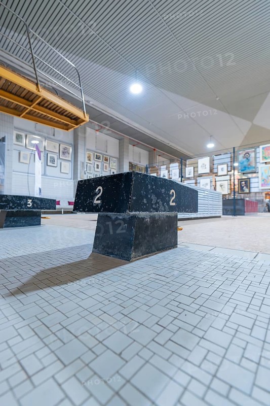 A dark winner's podium stands in an exhibition hall, surrounded by works of art and industrial lighting, historical art exhibition in the old swimming pool, Schaudepot, Calw, Black Forest, Germany