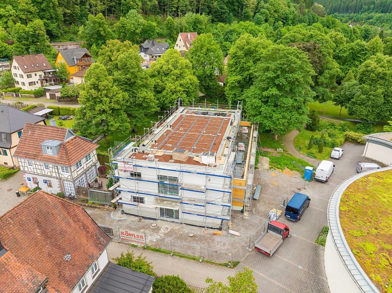 Building under construction with scaffolding, surrounded by trees and construction site vehicles, Hirsau, Calw, Germany