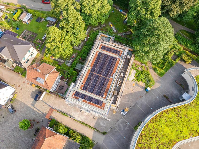 Aerial view of a construction site with solar modules on the roof, surrounded by gardens and houses, Hirsau, Calw, Germany