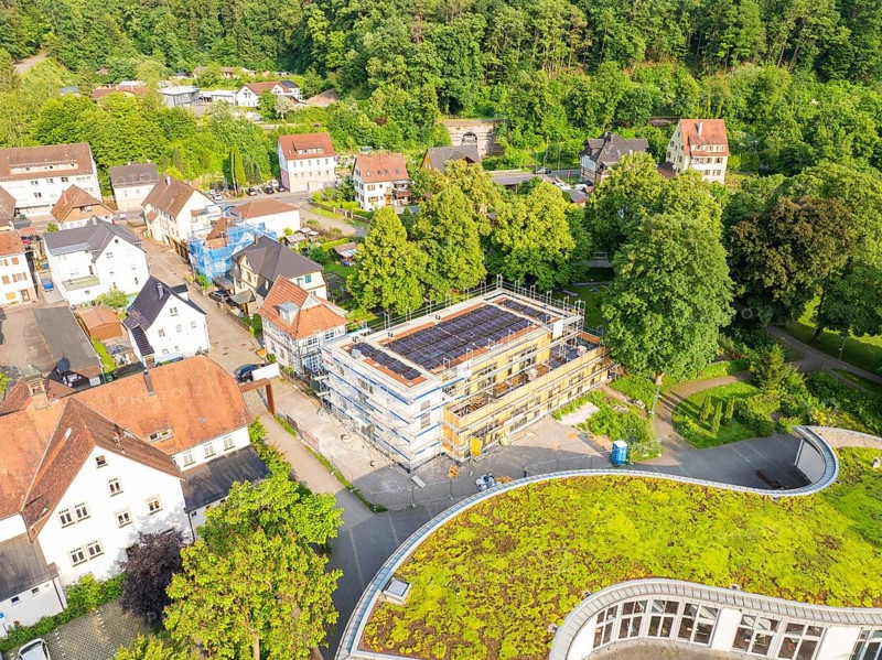 View of a residential area with a building site in the centre and green areas on some roofs, surrounded by trees, Hirsau, Calw, Germany