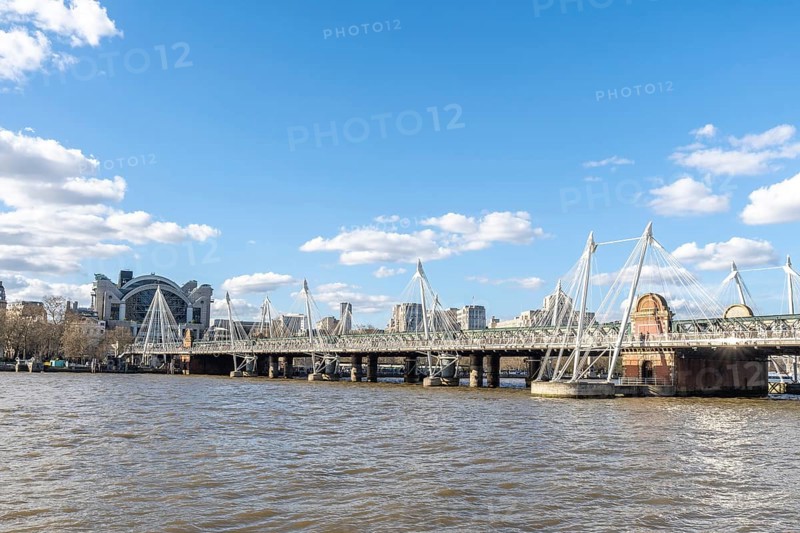 Modern pedestrian golden jubilee bridges flanking the railway hungerford bridge over the river thames with charing cross station in the background, london, uk