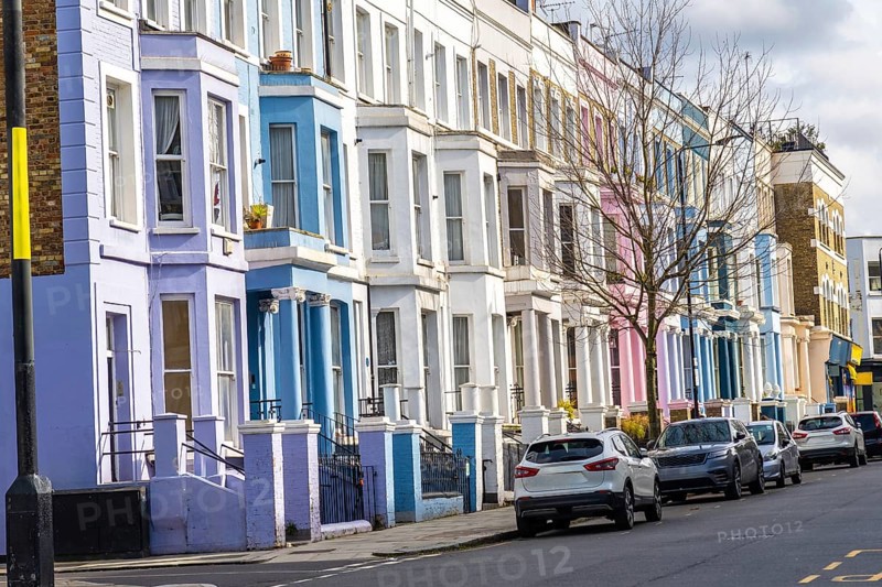 Pastel colored houses create a picturesque scene along a london street, showcasing the city's unique charm