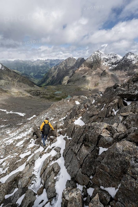 Mountaineer in rocky mountain landscape, at the summit of Keeskopf, behind summit of Petzeck, Hoher Perschitzkopf and Kruckelkopf, Schober group, Hohe Tauern National Park, Carinthia, Austria