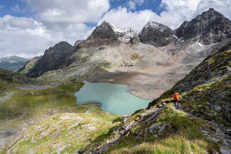 Mountaineer on hiking trail, view of turquoise-blue mountain lake Großer Gradensee, behind summit of Petzeck and Kruckelkopf, Schober group, Hohe Tauern National Park, Carinthia, Austria