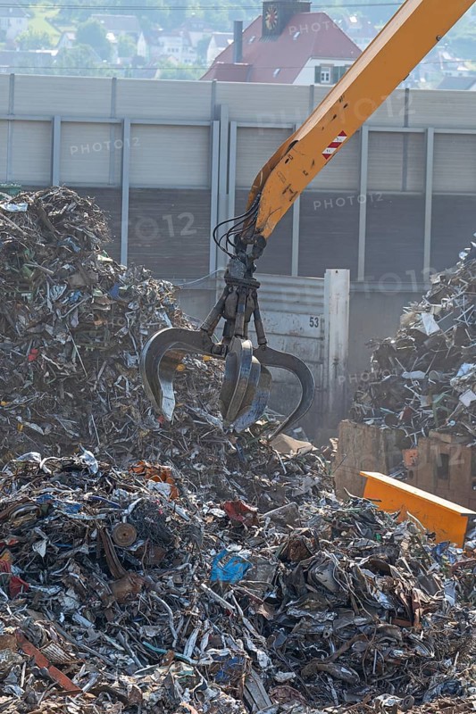 Hydraulic crane lifts scrap metal at the scrap yard in the background City of Plochingen