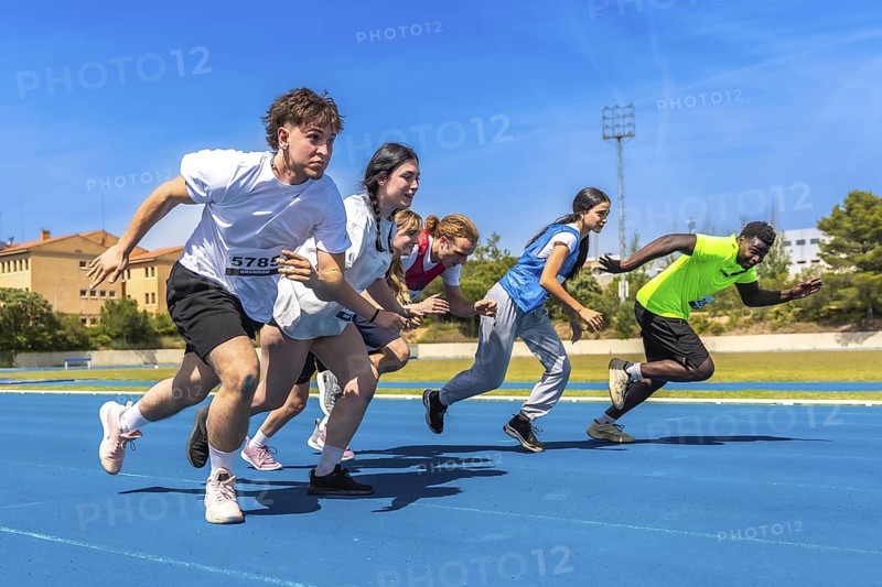 Diverse group of athletes sprinting on a vibrant blue running track under a bright sun, showcasing energy and determination in competition