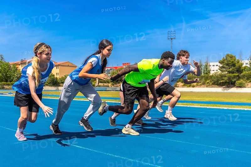 Young athletes sprinting energetically on a vibrant blue track under the bright sun, showcasing determination and competitive spirit