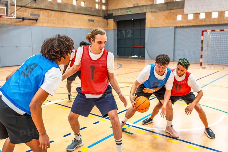 Young basketball players practicing in a gym, focusing on defense and attack strategies during a dynamic training session