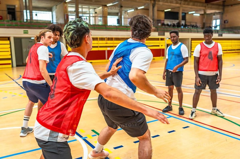 Young basketball players practicing in a gym, focusing on teamwork and skill development during a dynamic training session