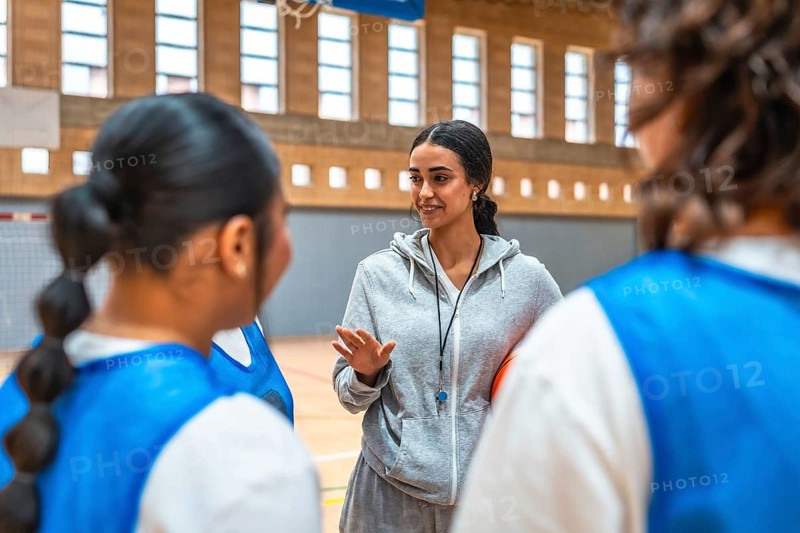 Basketball coach explaining game strategy to her team players during training in a basketball court