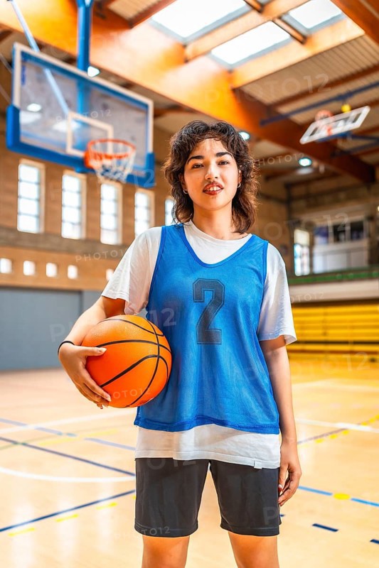 Young asian woman basketball player holding a ball in an indoor court, ready for training or competition