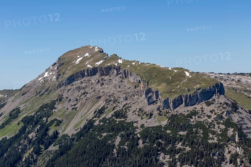 The rocky mountain peak Hohe Ifen and the Gottesacker plateau with snow and grass under a clear blue sky in Kleinwalsertal, Austria