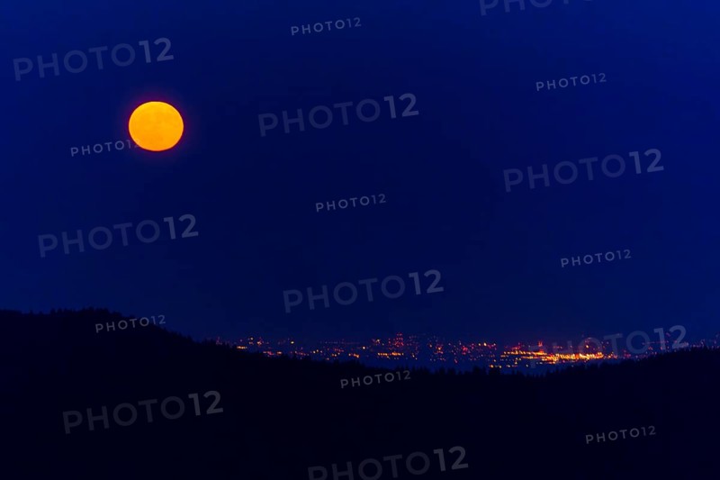 Full moon over a city with sparkling lights at night, full moon, strawberry moon 2025, Vosges, France