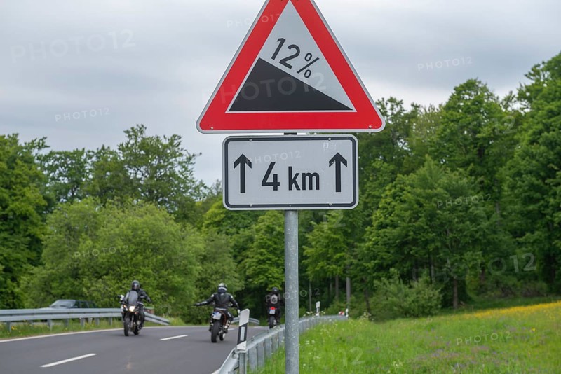 Road sign Gradient, gradient 12 per cent, length 4km, GEO nature park Park Frau Holle Land am Meissner, low mountain range, legendary figure, home of the fairy tale, motorcyclist, country road, crash barriers, forest, Kassel district, Fulda Werra Bergland, Germany