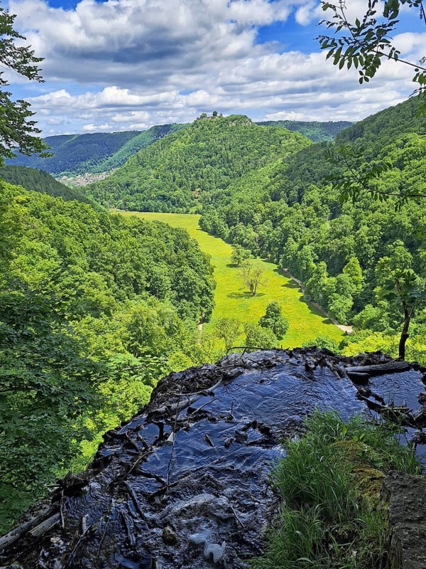 View from a hill onto a green valley (corn valley) with meadows, surrounded by wooded hills, Bad Urach