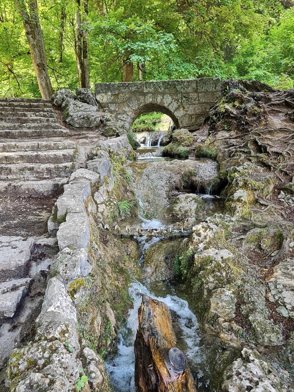 A small stone bridge over the Brühlbach, wild and romantic stream and source of the Urach waterfall with natural rock formations in the wooded area, Bad Urach
