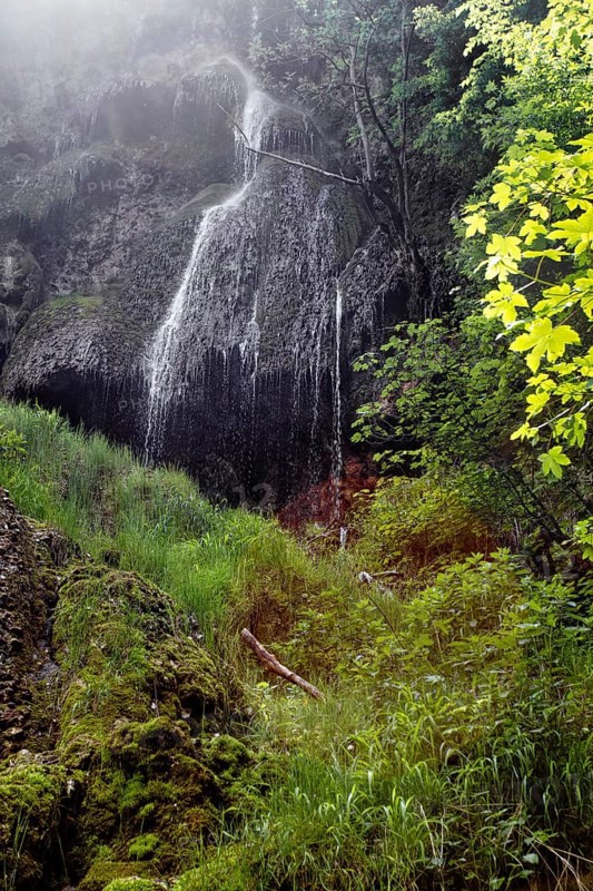 Refreshing waterfall (Urach waterfall) flows over rocks in lush green surroundings, Bad Urach
