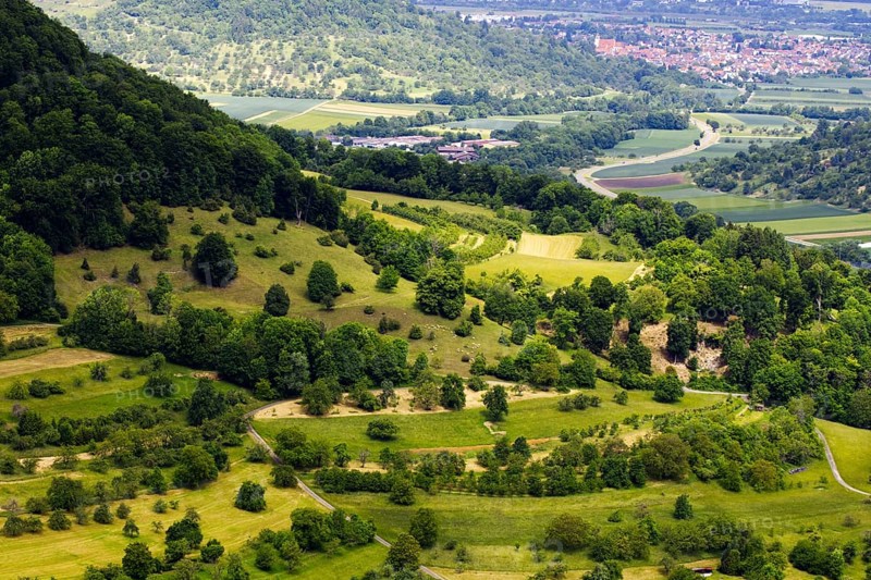 Hilly landscape with trees and a view of a distant town, Neidlingen