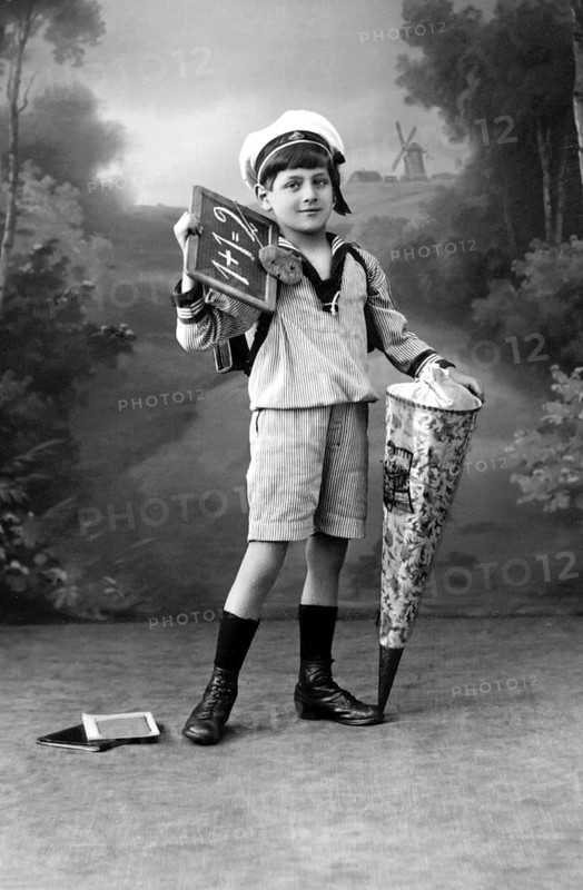 Boy with school cone, Boy in sailor suit with blackboard and school cone in front of landscape background, Historical photo