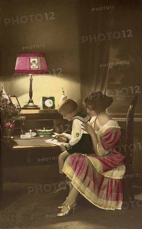 1910, Mother with child practising writing, child and mother at a desk in dim lamp light, historical photo