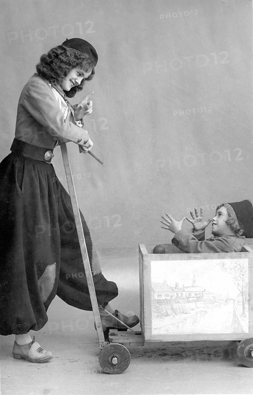 Nanny joking with child in wooden wagon, 1920, Girl pulling a little boy in a wooden toy wagon, both laughing and having fun, historical photo