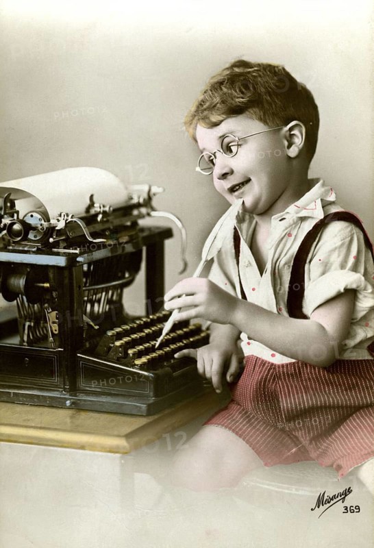 Boy at typewriter, 1920, Boy with glasses playing happily at an old typewriter, he seems to be imagining writing, historical photo