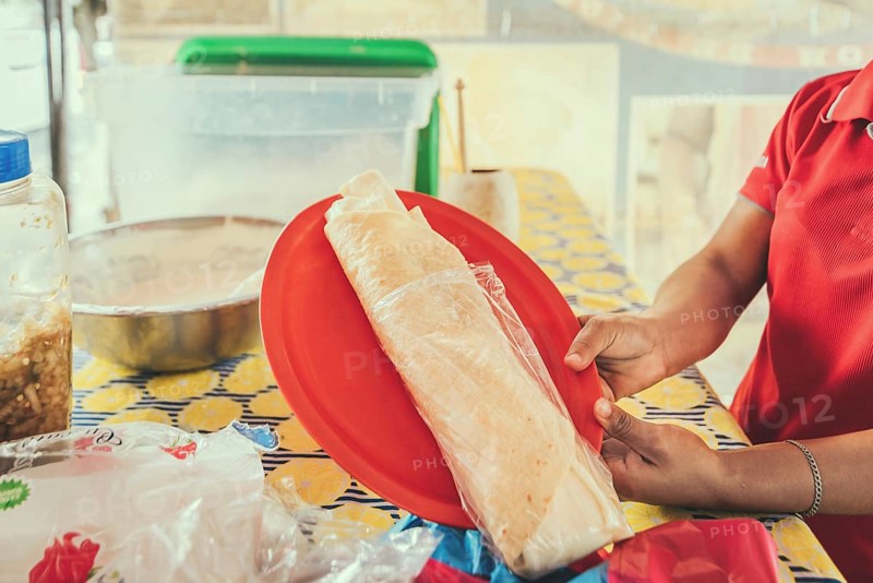 Hands of a person serving traditional quesillo. Vendor serving delicious quesillo in a bag