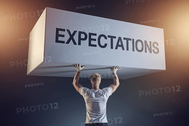 Man straining under block labeled expectations with work gloves, symbolizing male gender roles and societal pressure. Generative AI, AI generated