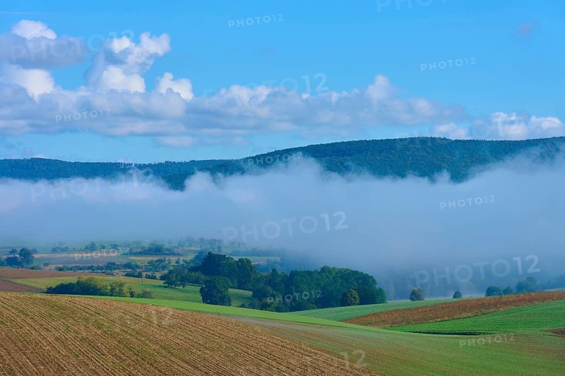 Fog moves through hilly landscape with blue sky, Mönchberg, Miltenberg, Spessart, Bavaria, Germany