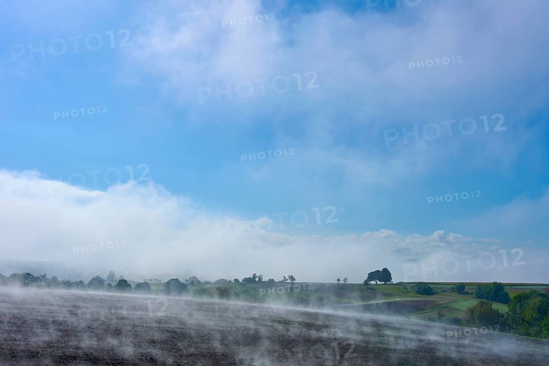 A wide landscape with fog, blue sky and trees in the distance, Schmachtenberg, Miltenberg, Spessart, Bavaria, Germany