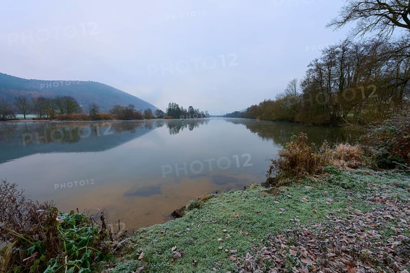 A calm winter river, with frozen banks and bare trees in the background, Laudenbach, Main, Spessart, Odenwald, Bavaria Germany