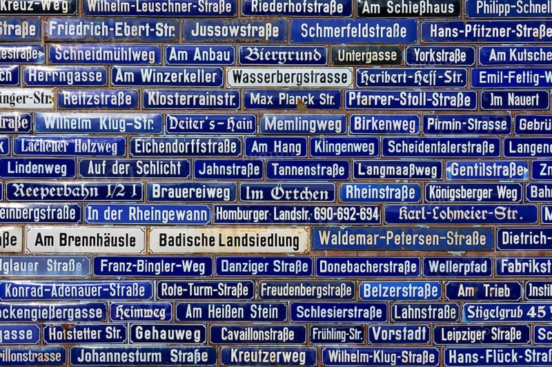 Dense collection of blue street signs with various street names, Amorbach, Odenwald, Bavaria, Germany