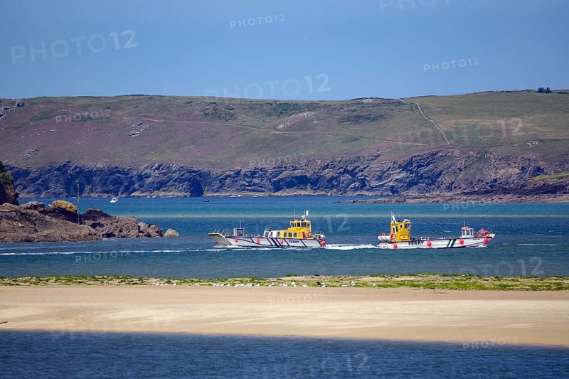Two small passagi in blue water against a rocky coastline and green cliffs, Camel Trail, Padstow, Cornwall, Cornwall, England, United Kingdom