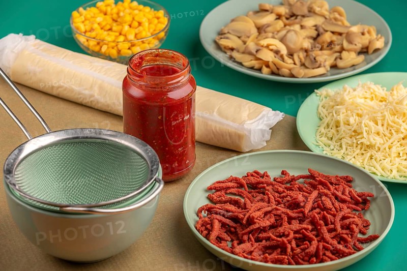 Ingredients for preparing a pizza arranged on a green table