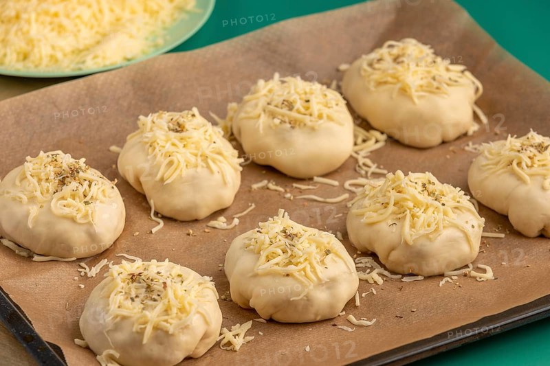 Raw pizza, balls with grated cheese and oregano on baking paper, ready for the oven