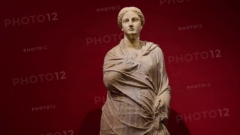 Marble statue of a woman in draped shawls, depicted against a red background, Archaeological Museum, Kos Town, Kos, Dodecanese, Greek Islands, Greece