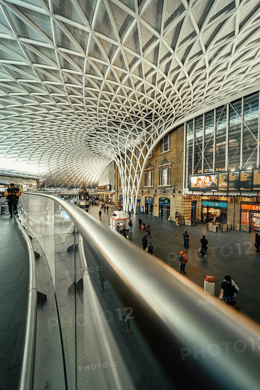 Wide angle view of a busy train station with glass roof and escalators, King's Cross Station, London, United Kingdom, World