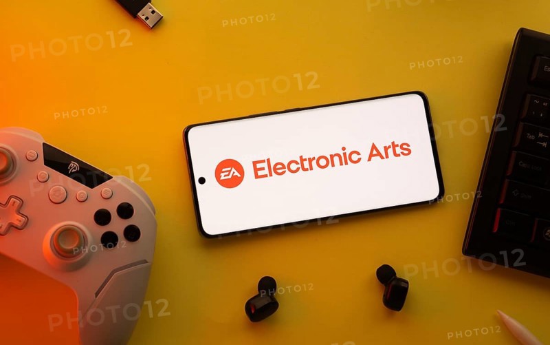 Dhaka, Bangladesh- 23 March 2025: Electronic Arts logo displayed on a smartphone surrounded by gaming accessories in an yellow light