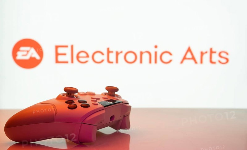 Dhaka, Bangladesh- 20 Mar 2025: A close-up of a white gamepad with the Electronic Arts seen on screen in the background