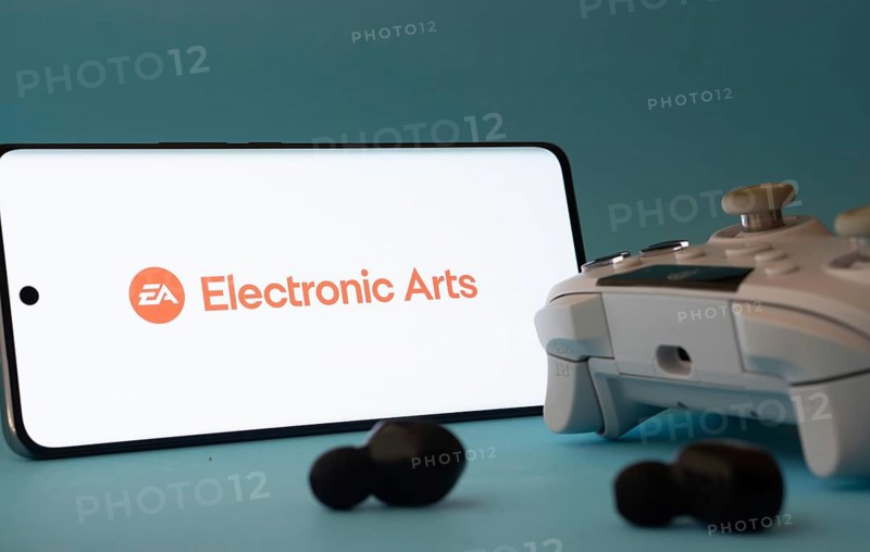 Dhaka, Bangladesh- 23 Mar 2025: A smartphone with a Electronic Arts icon next to a controller and earbuds on a blue surface