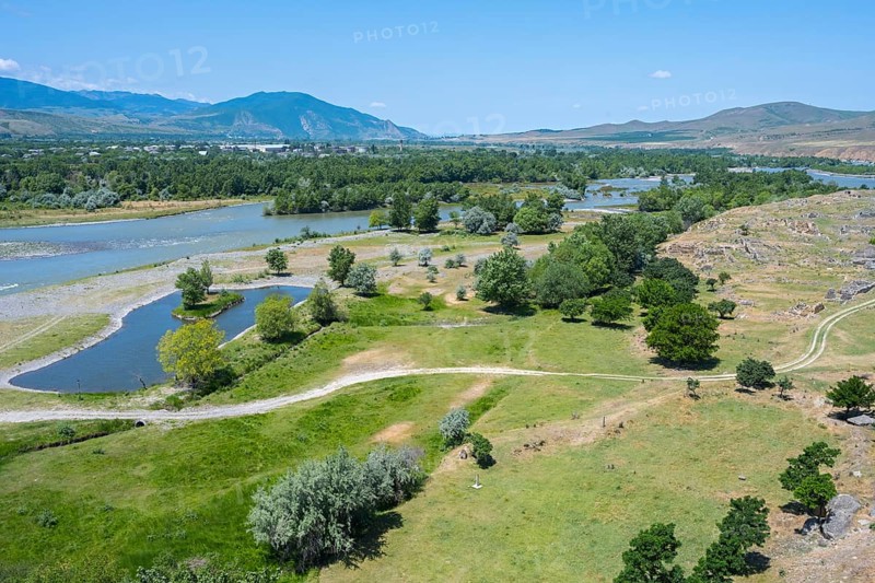 Wide landscape with river, green fields and hills under a blue sky, view from the cave town of Uplistsikhe, Kura or Mtkwari river, Inner Kartli region, Shida Kartli, Georgia