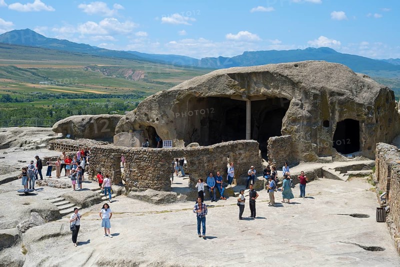 Tourists visit old caves and rock formations on a sunny day, Tamaris Darbasi, Tamara's Hall, Uplistsikhe cave town, Innerkartli region, Shida Kartli, Georgia